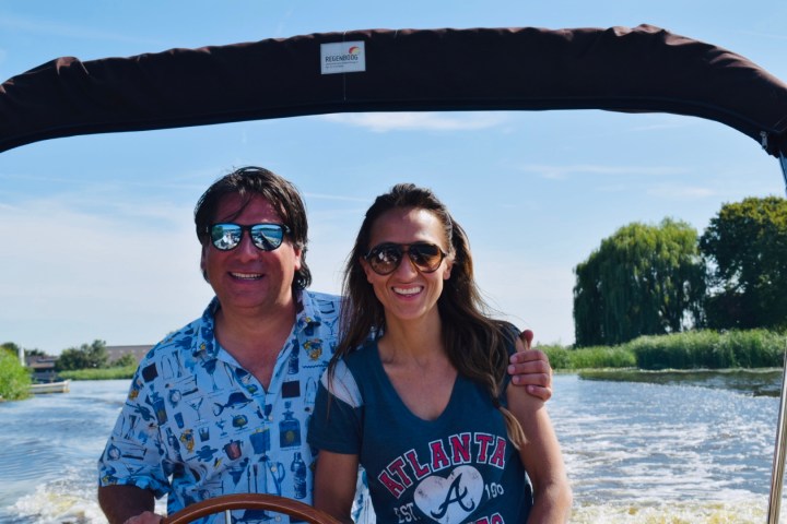 Two people next to each other behind steering wheel on a boat