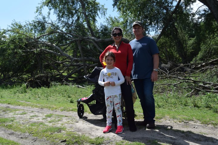 Two adults and a child standing next to a push chair
